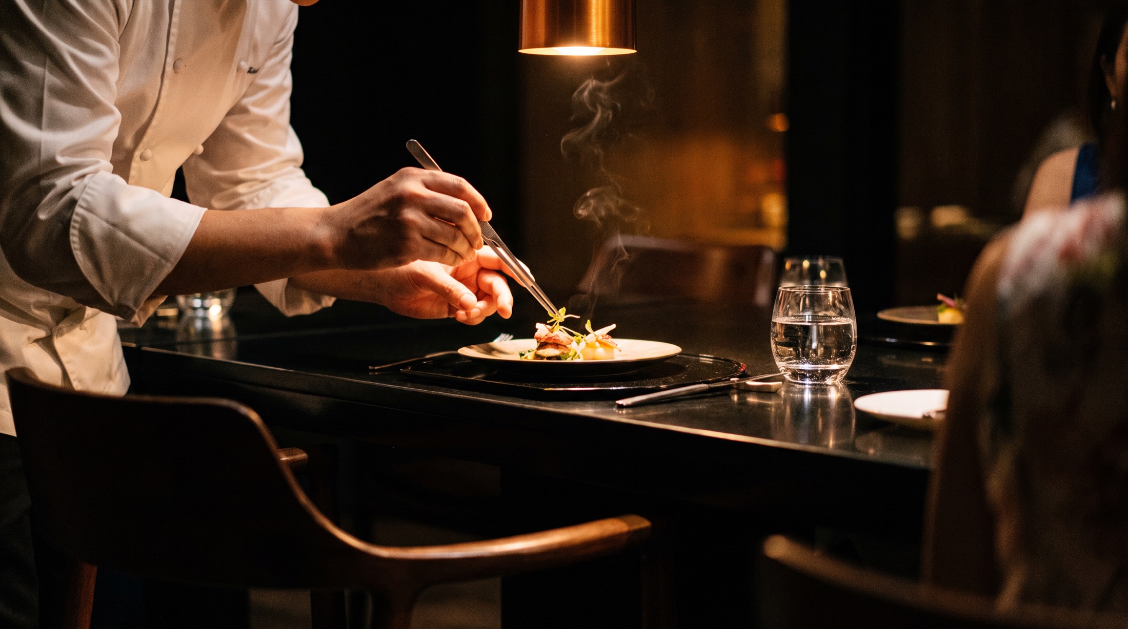 A chef plates a course at a candlelit chef's counter